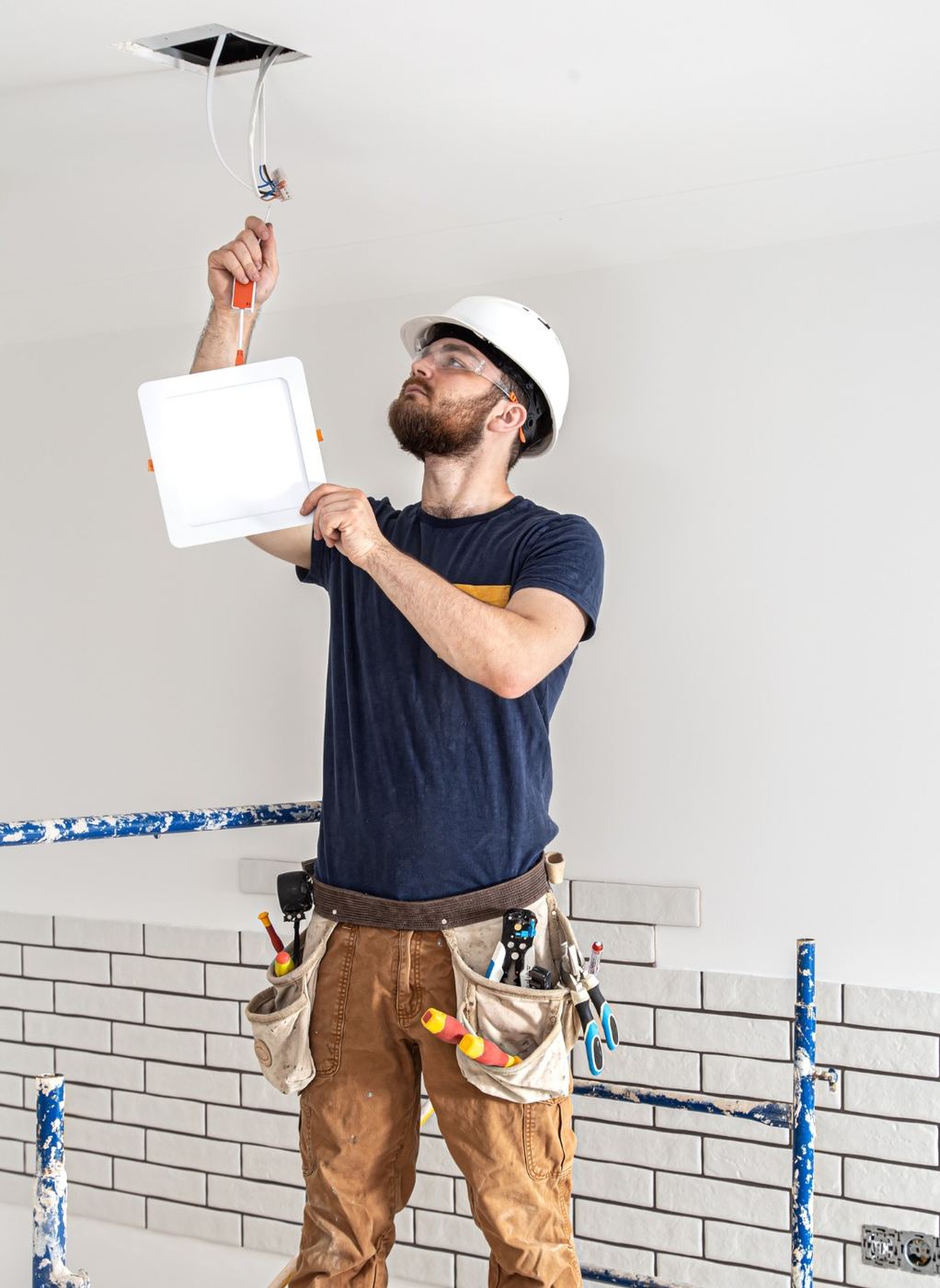 Electrician installing a ceiling light panel in a bright home